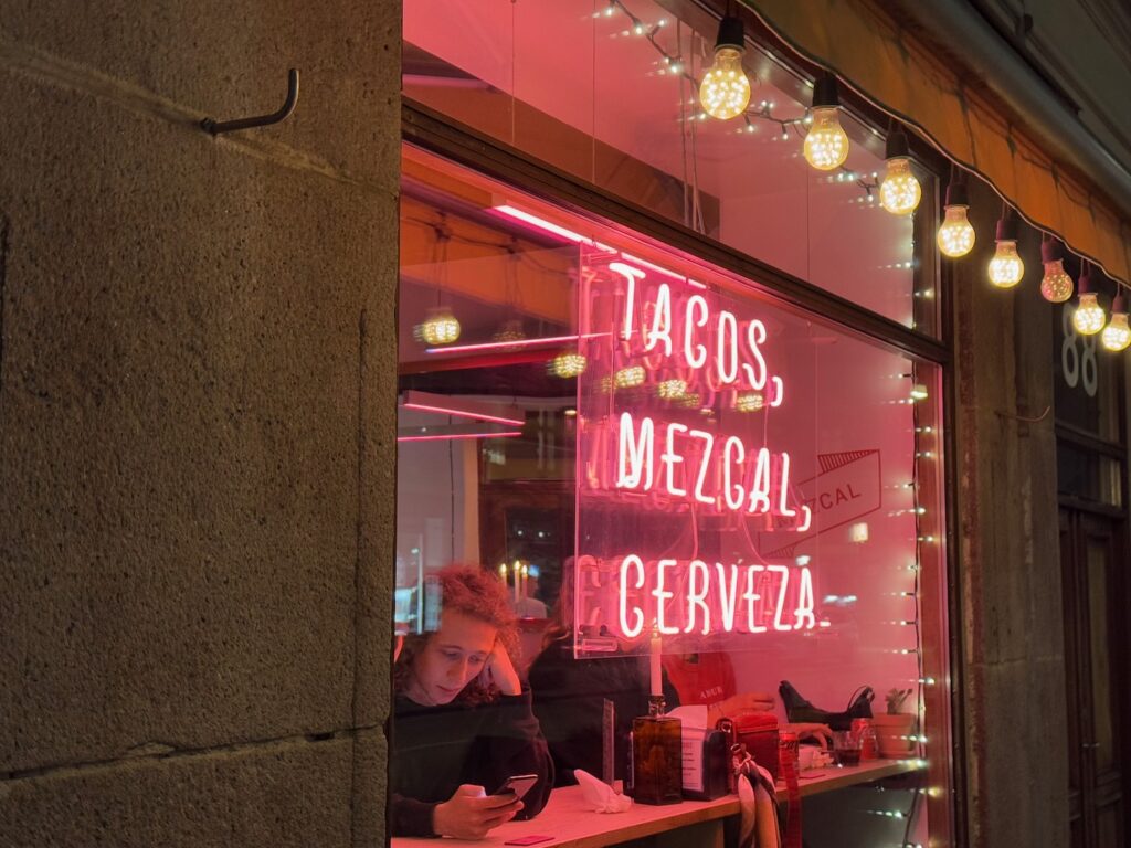 a woman sitting at a table in front of a window with a sign