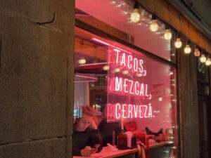 a woman sitting at a table in front of a window with a sign
