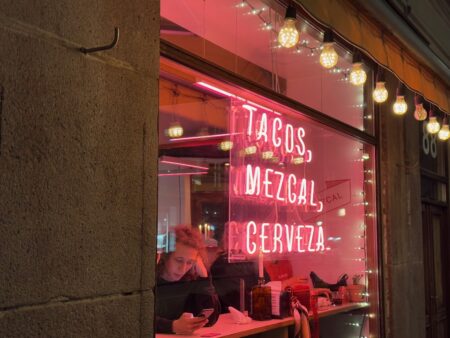 a woman sitting at a table in front of a window with a sign