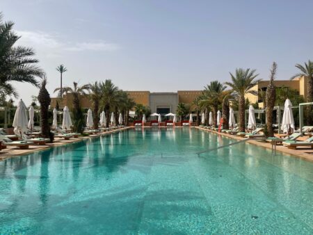 a swimming pool with palm trees and umbrellas